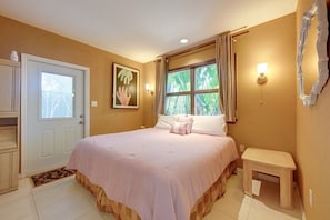 A bedroom with a bed, a bedside table, a door, a window with curtains, and a wall-mounted light fixture. - Peaceful And Private Unit, With Cover Parking (Sarasota)