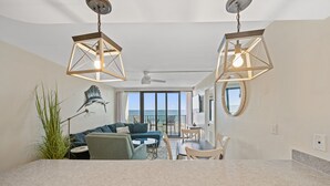 Ein geräumiger Wohnbereich mit großem Fenster, Deckenventilator und zwei Pendelleuchten.