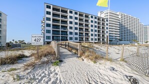 Ein Strandhotel mit mehreren Etagen, einer Holzpromenade, die zum Eingang führt, und einem Schild mit der Adresse.