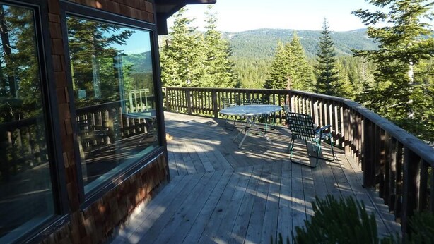 A wooden deck with a table and chairs, overlooking a forested area with mountains in the distance. - Large Home, Lovely Lake Views, Great Getaway (Tahoma)
