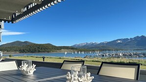 Un área de comedor al aire libre con vistas a un lago y montañas.