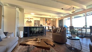 Un salón amplio con sofá, una mesa de centro, una silla y una zona de comedor al fondo.