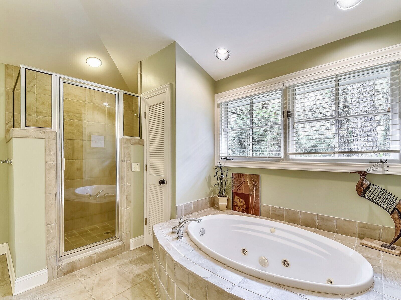 A bathroom with a walk-in shower, a bathtub, and a window with blinds.