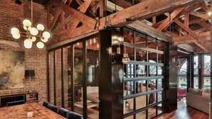 A modern interior with exposed wooden beams, a large wooden table, and a glass partition.