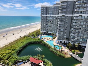 A hotel with a pool, beach, and ocean view.