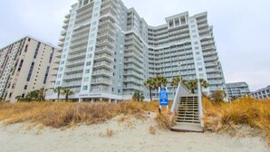 A high-rise hotel with multiple balconies and a beach view.