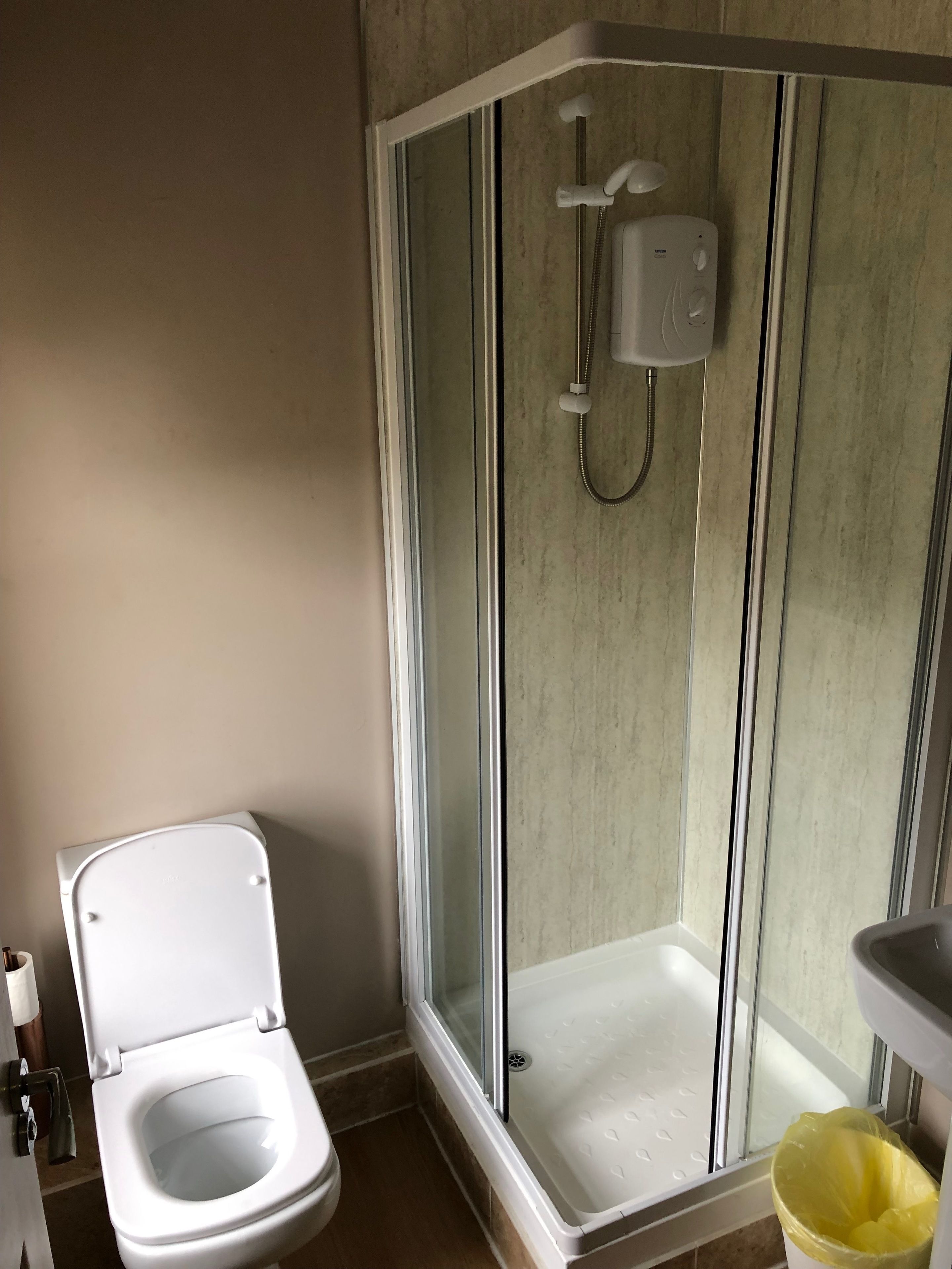 A modern bathroom with a glass-enclosed shower, a toilet, and a sink.