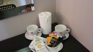 Frühstücksaufstellung mit zwei weißen Tassen, einer weißen Kanne und einem Teller mit Keksen und Teebeuteln.