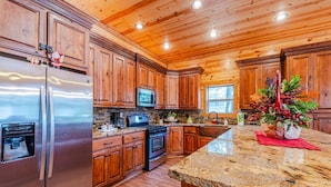 Una cocina moderna con armarios de madera, electrodomésticos de acero inoxidable, encimeras de granito y una isla central.