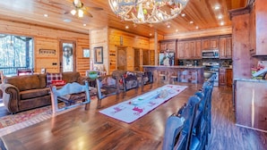 Interior espacioso de una cabaña de troncos con comedor, cocina y zona de estar.
