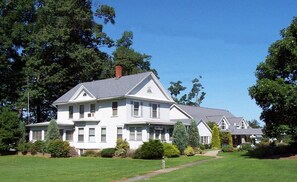 Una casa grande y blanca de dos pisos, con un césped bien cuidado y árboles al fondo, identificada como The Oak Park Inn.