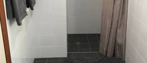 A small, tiled bathroom with a shower area, a towel rack with two towels, and a shower curtain.