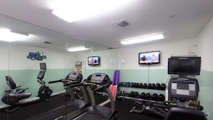 Ein Fitnessstudio mit Laufbändern, Crosstrainern und einer Gewichtbank.