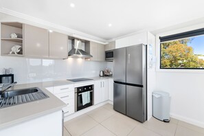 A modern kitchen with a stainless steel refrigerator, built-in oven, and a microwave.