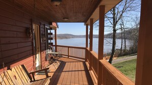 A wooden deck with a view of a lake, a table with chairs, and a bench. - Exceptional views of the Ohio River and accommodates 2 boats (Magnet)
