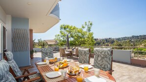 Une terrasse avec une table préparée pour le petit-déjeuner, des sièges extérieurs et une vue panoramique.