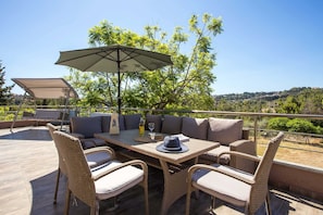 An outdoor patio with wicker furniture, a table, and a large umbrella.
