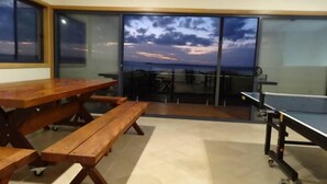 Un balcón con mesa y bancos, una mesa de ping pong y vista al cielo.