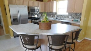 A kitchen with a central island, stainless steel appliances, and a potted plant.