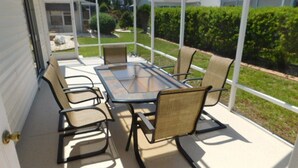 A covered patio with a glass-top table and four chairs.