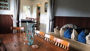 Una mesa de madera con sillas, un jarrón y una pequeña pila de cartas.