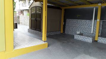 A covered outdoor area with a tiled floor, a brown door, and a tiled wall.