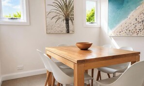 A dining area with a wooden table, white chairs, and a bowl on the table.