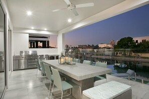 Cocina exterior moderna con comedor y vista a un paisaje urbano y una piscina.