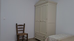 Una habitación con una silla de madera, un armario y una cama.