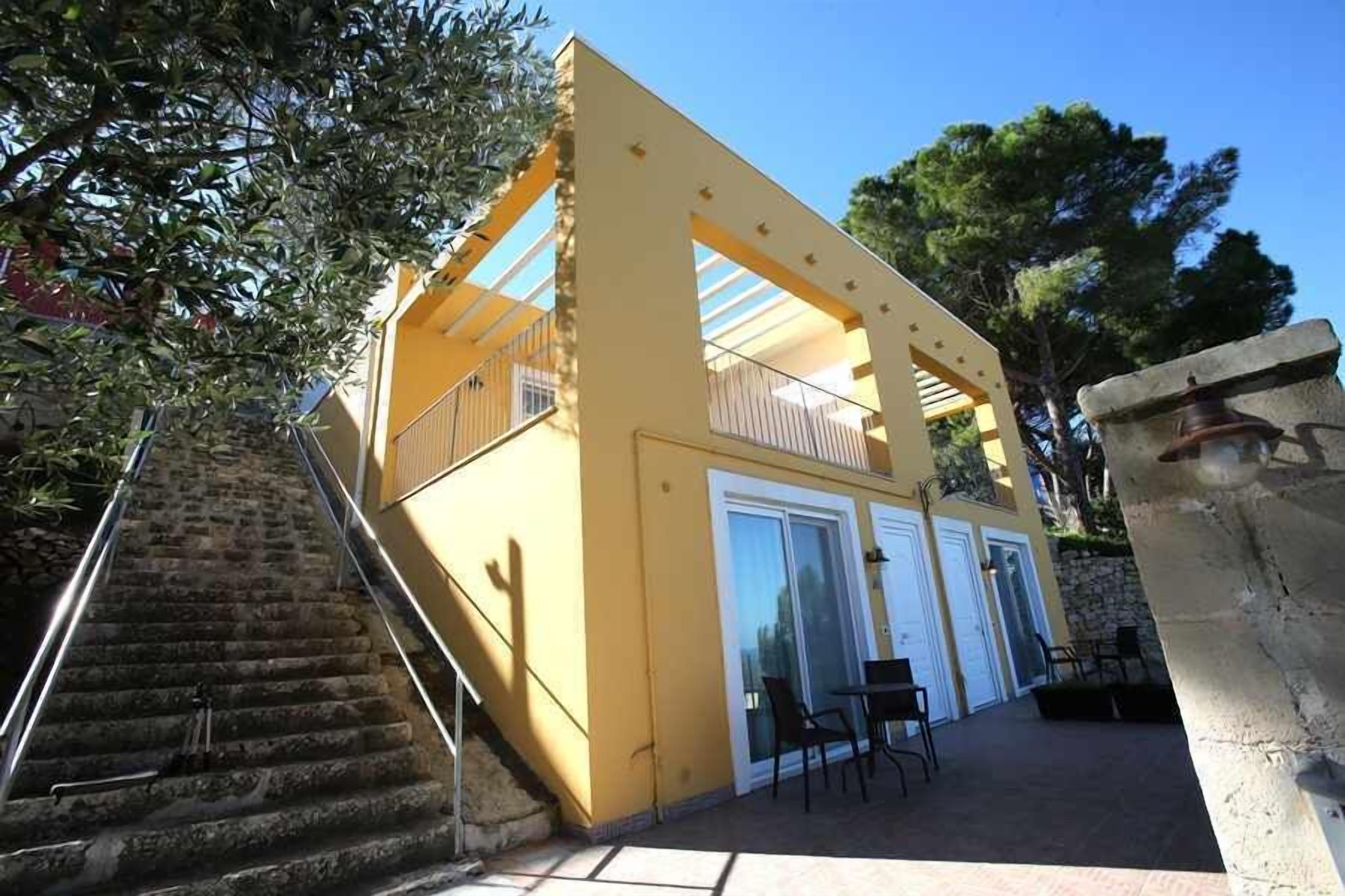 A yellow building with a staircase leading to a balcony.