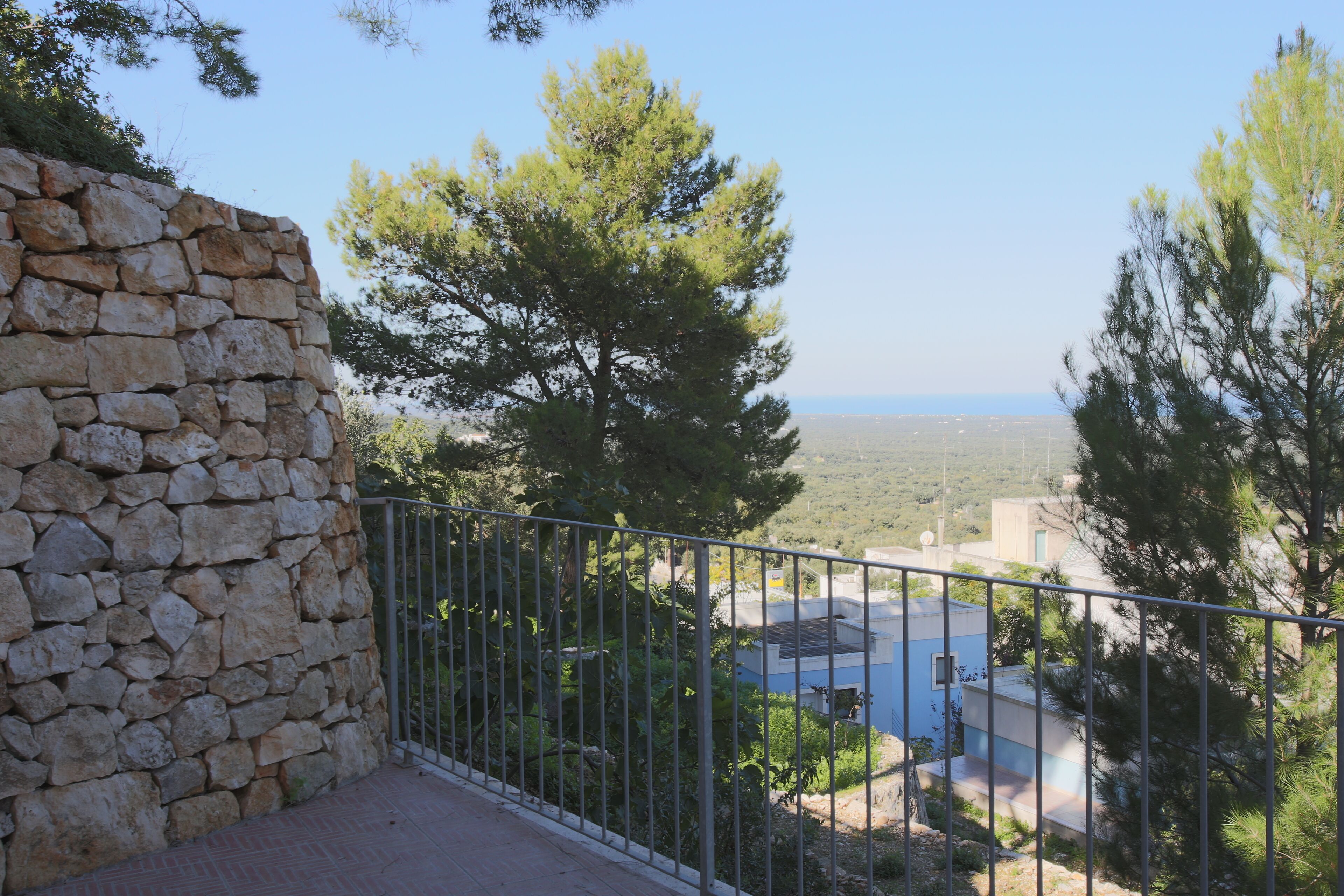 A stone wall, a metal railing, and a view of a distant landscape.