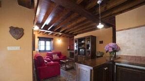 A living room with red sofas and a kitchen area with dark wooden cabinets and a tiled backsplash. - Rural house El Campón de San Martín II for 4 people (Piloña)
