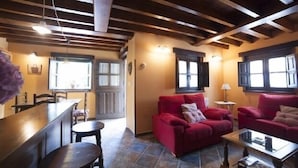 A cozy living area with a red sofa, a coffee table, and a wooden dining table. - Rural house El Campón de San Martín II for 4 people (Piloña)