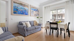 En stue med en stribet sofa, et spisebord med stole og to billeder på væggen.