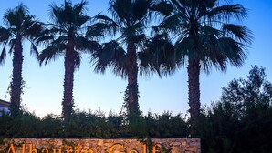 A stone wall with the text "Alhourtin Golf" and palm trees in the background. - Cozy apartment with beautiful view on golf course, mountains and nature reserve. (Alhaurin El Grande)