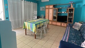 A living room with a dining area, a sofa, and a TV.