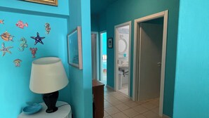 A hallway with teal walls, a framed painting, and starfish decorations.