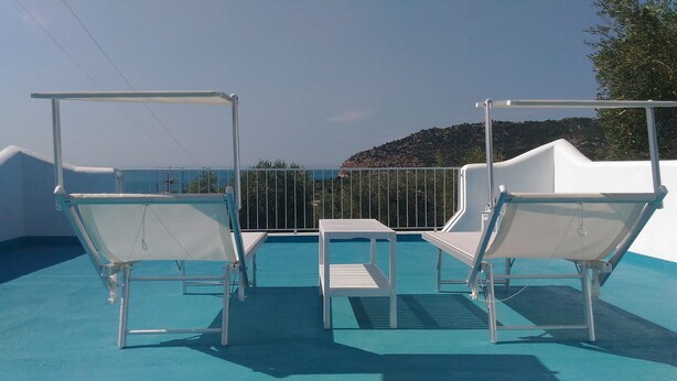 A poolside area with two white lounge chairs and a small table, overlooking a scenic view with a hill in the background. - CASA VACANZE A MATTINATA - GARGANO (Mattinata)