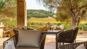 An outdoor dining area with wicker chairs and a table set for a meal, overlooking a scenic landscape. - Cozy estate "It's Bellveret" (Manacor)