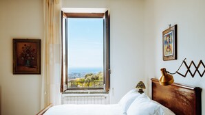 A bedroom with a large window, a bed, a nightstand, and a view of the city. - For 8 people Monticelli-Mansion (casola di napoli)