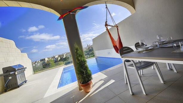 A patio area with a pool, a barbecue grill, and a dining table with chairs. - Three bedroom, luxury apartment with private pool (Ix-Xagħra)