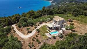Une villa avec piscine, entourée d’une végétation luxuriante et offrant une vue sur la mer.