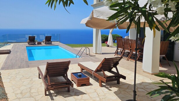 Un espace piscine avec des chaises longues et une vue sur l’océan.