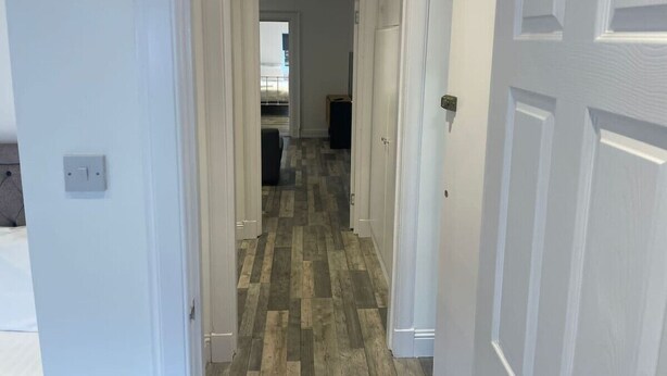 Un pasillo con piso de madera que lleva a una zona de cocina.