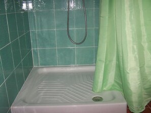 Une salle de bain avec une baignoire blanche, des carreaux verts et un rideau de douche vert.