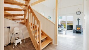 A wooden staircase leading to a living area with a fireplace, a pet feeding station, and a view of the outdoors. - Awesome home in OstseeResort Olpenitz with sauna (OstseeResort Olpenitz)