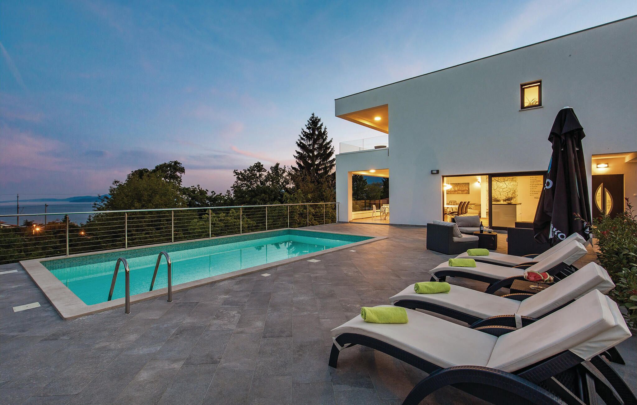Ein moderner Poolbereich im Freien mit Liegestühlen und Meerblick.