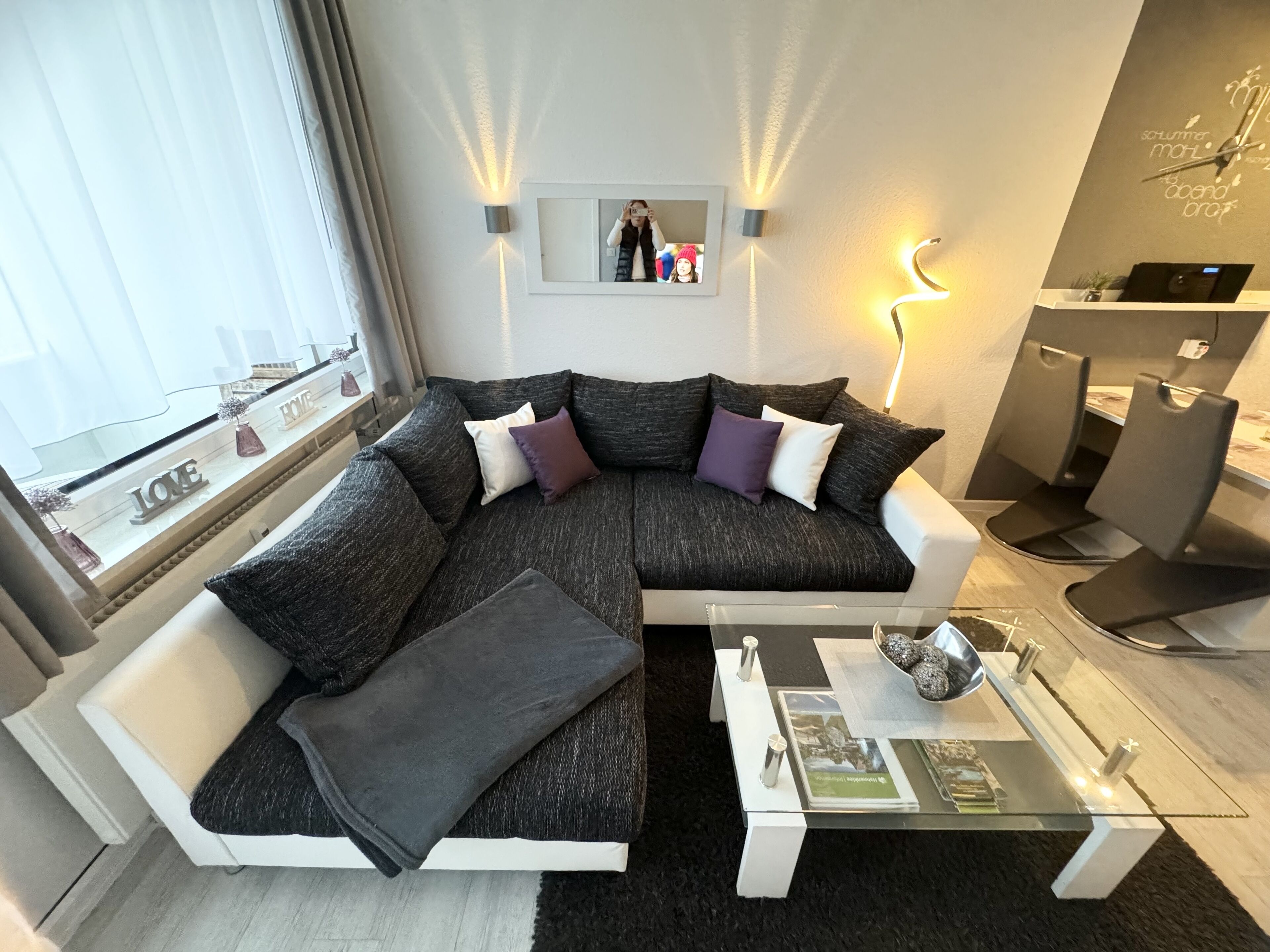 A modern living room with a sectional sofa, a glass coffee table, and a desk with a chair.