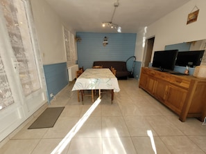 A dining area with a table set for four, a sofa, and a TV on a wooden cabinet. - 2-bedroom gîte for 5 to 7 people in Sarlat. Heated swimming pool. Free WIFI. (SARLAT LA CANEDA)