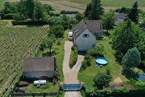 Uma casa grande com jardim, piscina e vinhedo.